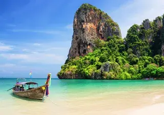 Thai traditional wooden longtail boat and beautiful sand beach Canva Pro